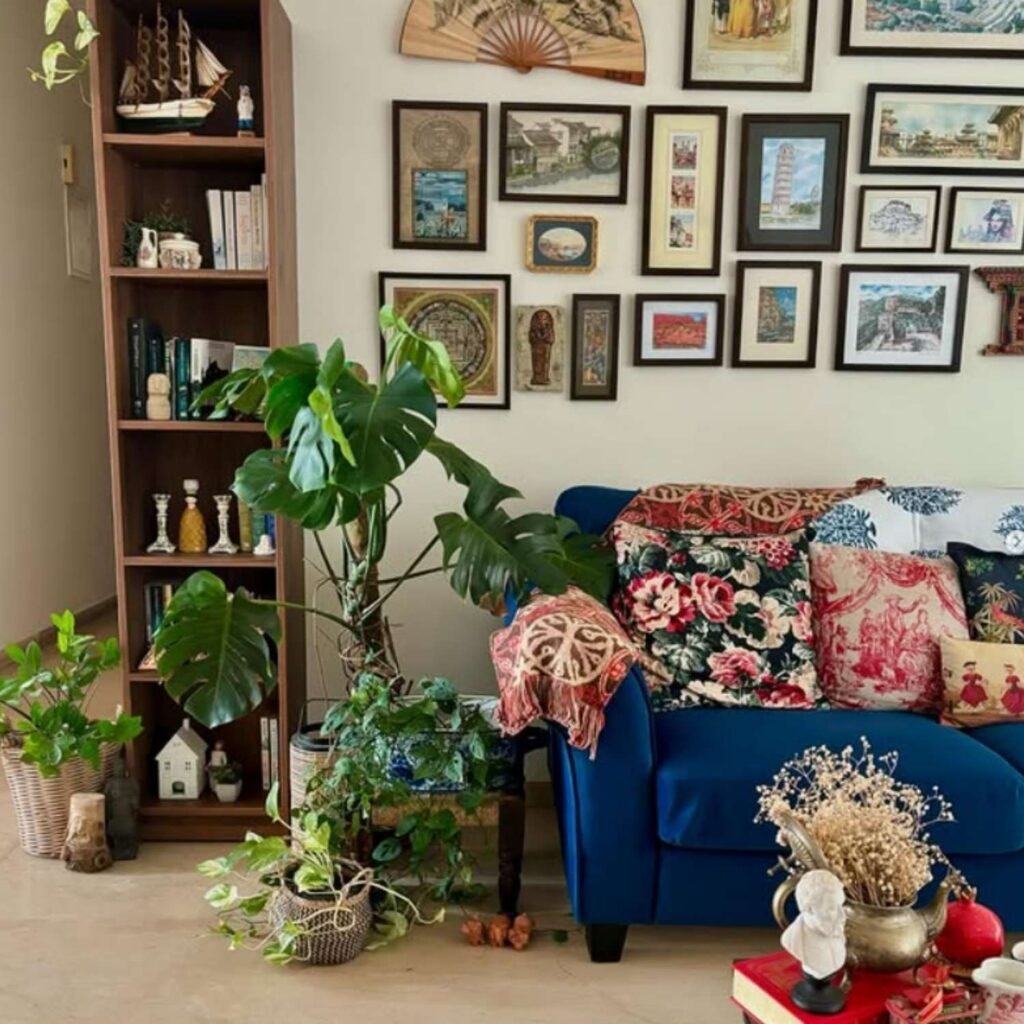 Blue sofa in eclectic living room with gallery wall, bookshelves, and layered colorful cushions.