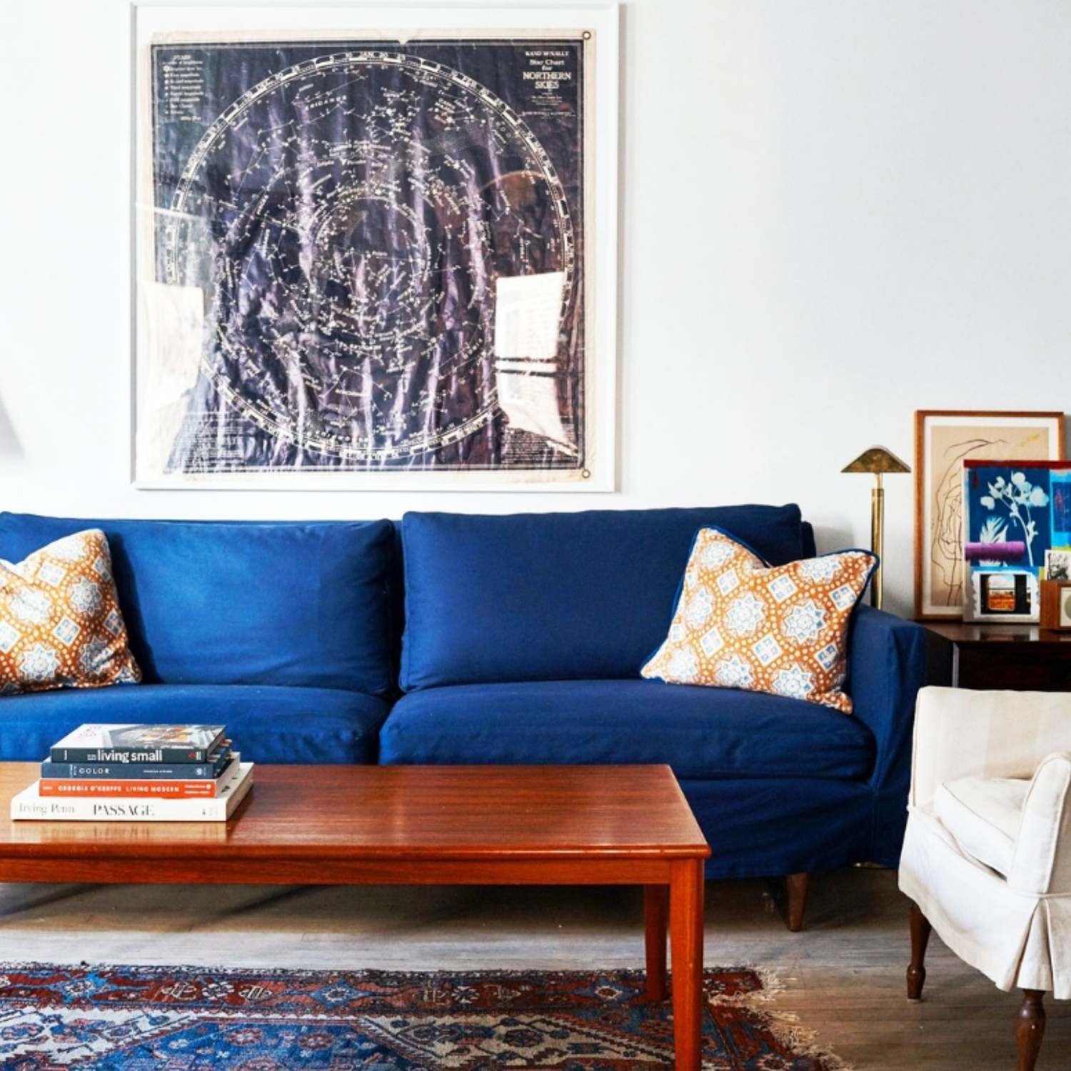 Deep blue sofa styled with framed artwork and wooden coffee table in a modern living room.