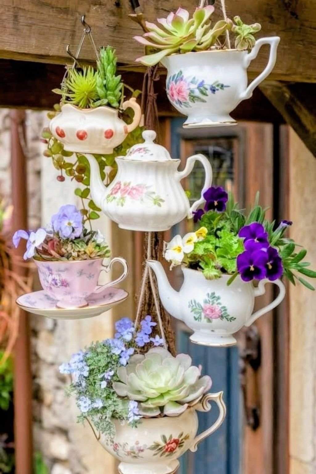 hanging teacup planters arranged vertically with flowers