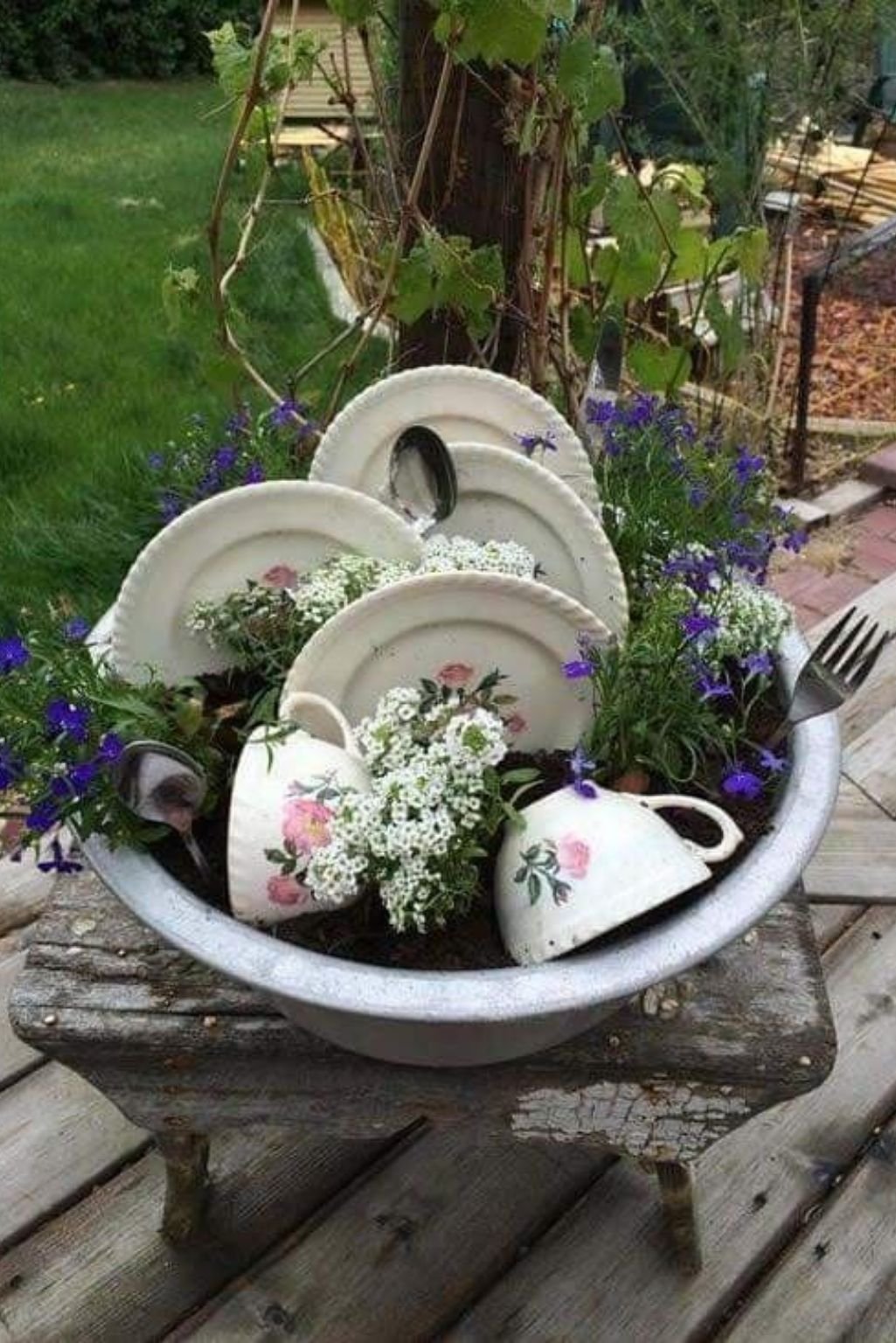 garden table decorated with teacups, plates, and small plants