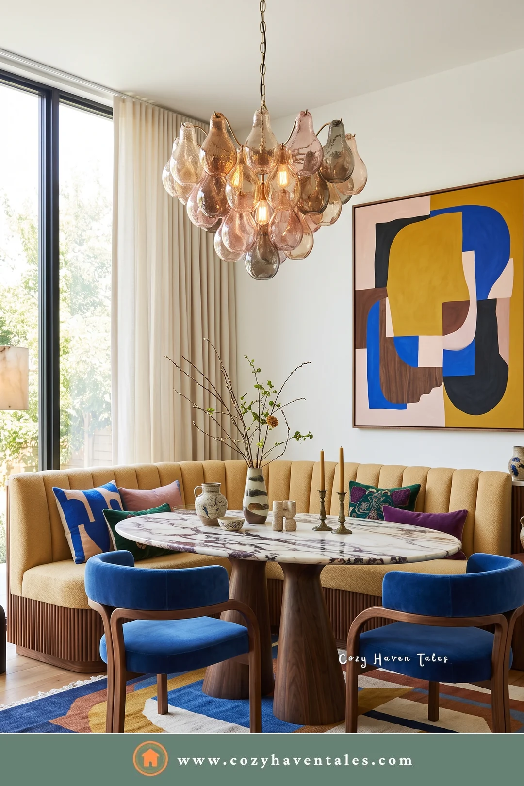 Butter yellow curved banquette with blue velvet chairs, a marble table, and a pink glass chandelier
