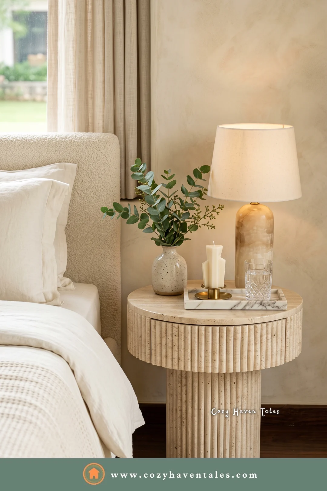 Cream fluted pedestal bedside table with a round top, a glass lamp, and eucalyptus