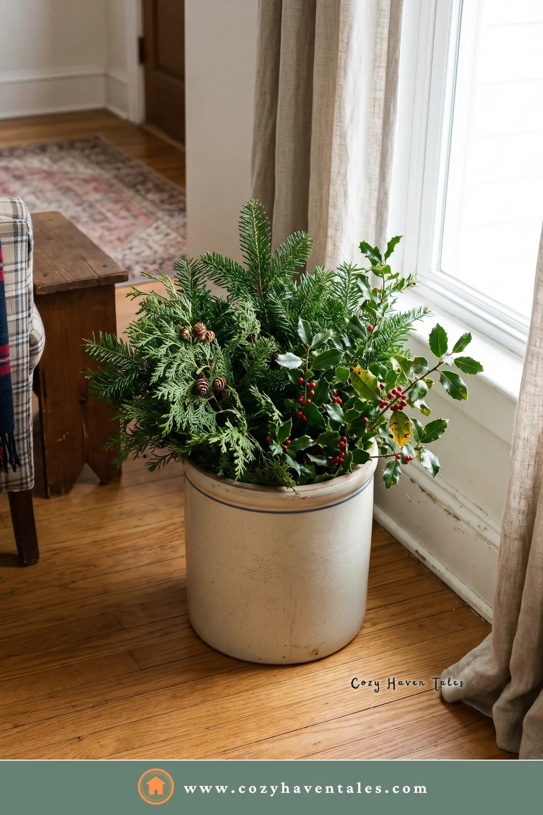 Fresh fir, cedar, and holly branches arranged loosely in a cream stoneware crock beside a window