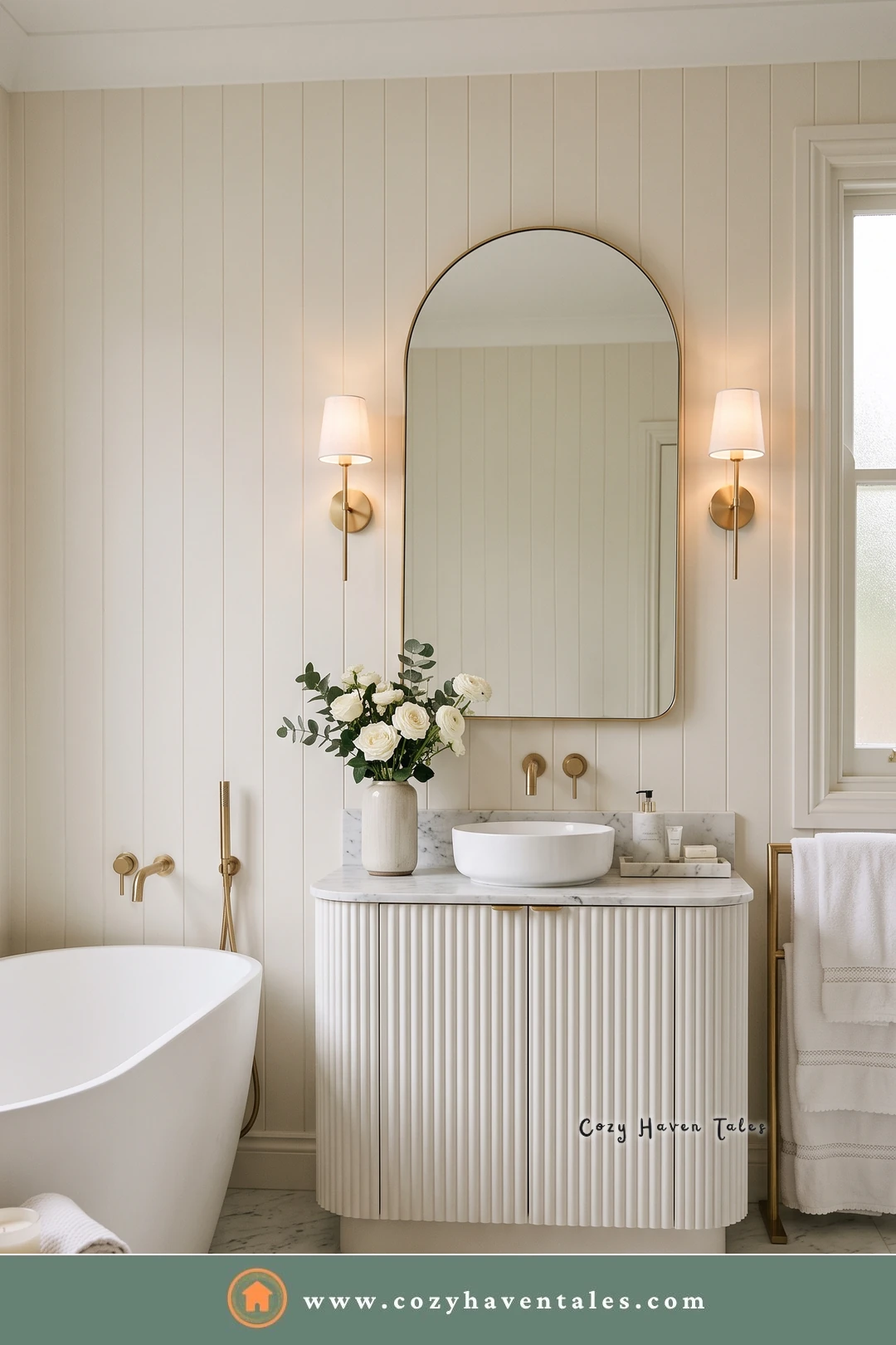 Cream and white bathroom with a fluted vanity, a vessel sink, an arched brass mirror, and brass sconces